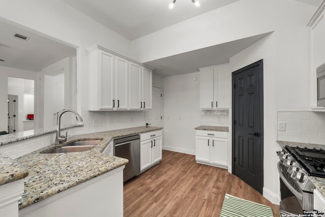 kitchen featuring white cabinets, tasteful backsplash, light hardwood / wood-style flooring, stainless steel appliances, and sink