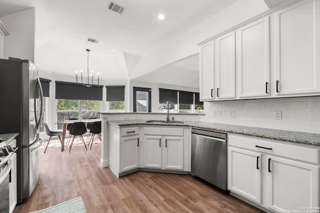 kitchen featuring appliances with stainless steel finishes, white cabinetry, light stone countertops, light hardwood / wood-style flooring, and sink