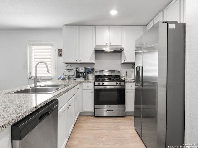 kitchen featuring light hardwood / wood-style flooring, sink, light stone countertops, white cabinets, and appliances with stainless steel finishes