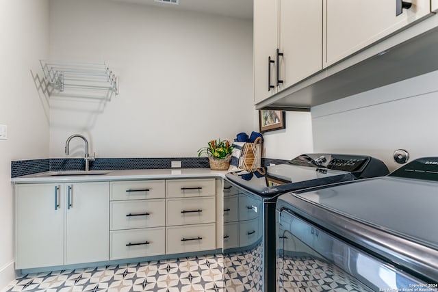 washroom with sink, cabinets, and washer and clothes dryer