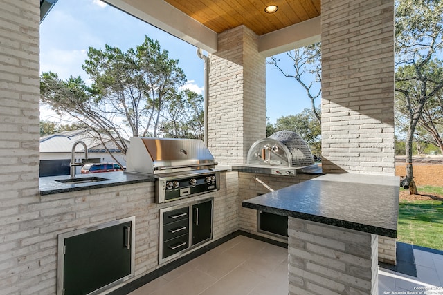 view of patio featuring exterior kitchen, sink, and a grill