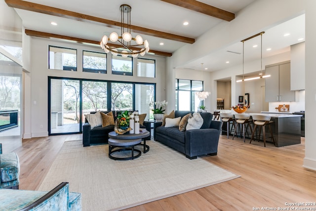 living room featuring light hardwood / wood-style floors, a chandelier, plenty of natural light, and beamed ceiling