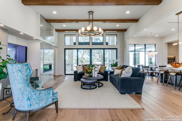 living room with light hardwood / wood-style floors, a chandelier, and beamed ceiling