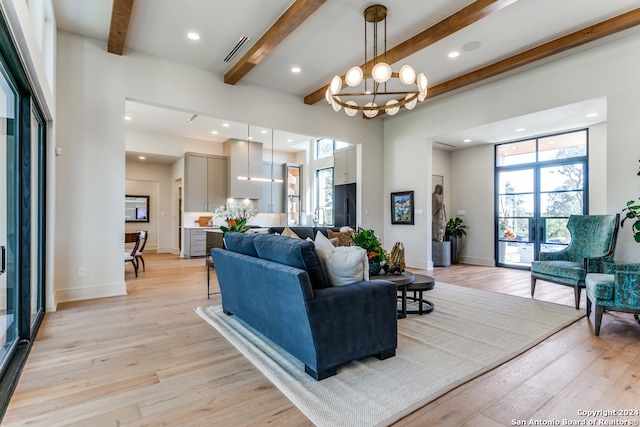 living room featuring beam ceiling, french doors, light hardwood / wood-style flooring, and an inviting chandelier