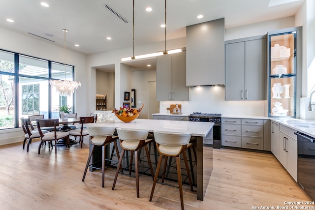 kitchen featuring gas range, light hardwood / wood-style floors, a kitchen bar, and gray cabinetry