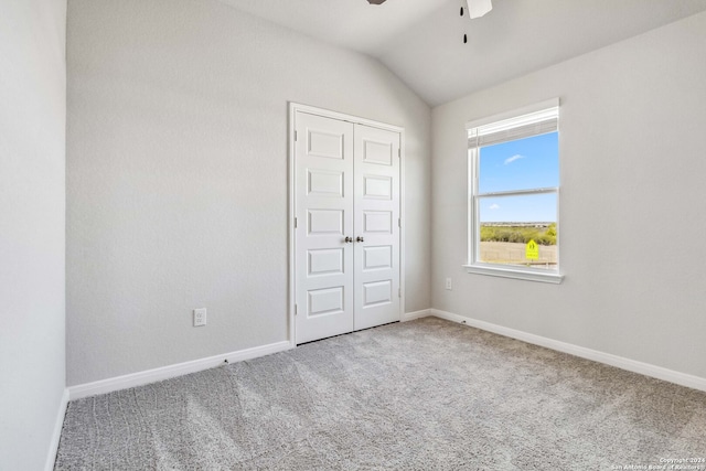 unfurnished bedroom with ceiling fan, carpet flooring, a closet, and vaulted ceiling