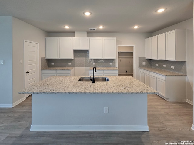 kitchen with a center island with sink, white cabinetry, sink, and hardwood / wood-style floors