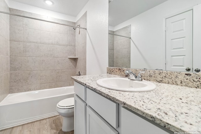 full bathroom with hardwood / wood-style flooring, vanity, toilet, and tiled shower / bath