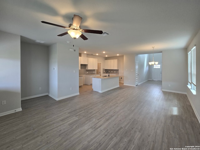 unfurnished living room featuring ceiling fan with notable chandelier, wood-type flooring, and sink