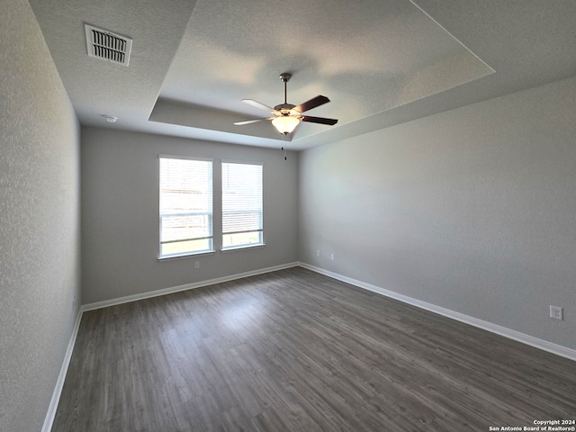 spare room featuring ceiling fan, a tray ceiling, a textured ceiling, and dark hardwood / wood-style floors