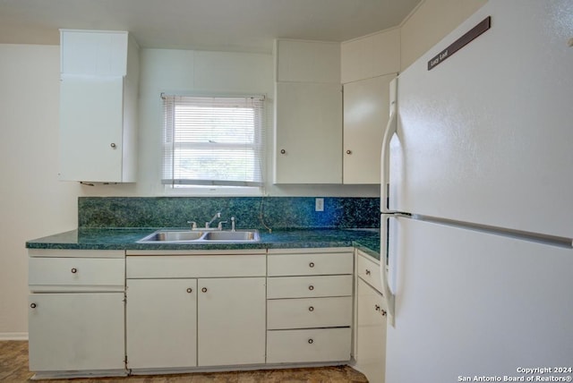 kitchen featuring white cabinets, sink, and white fridge