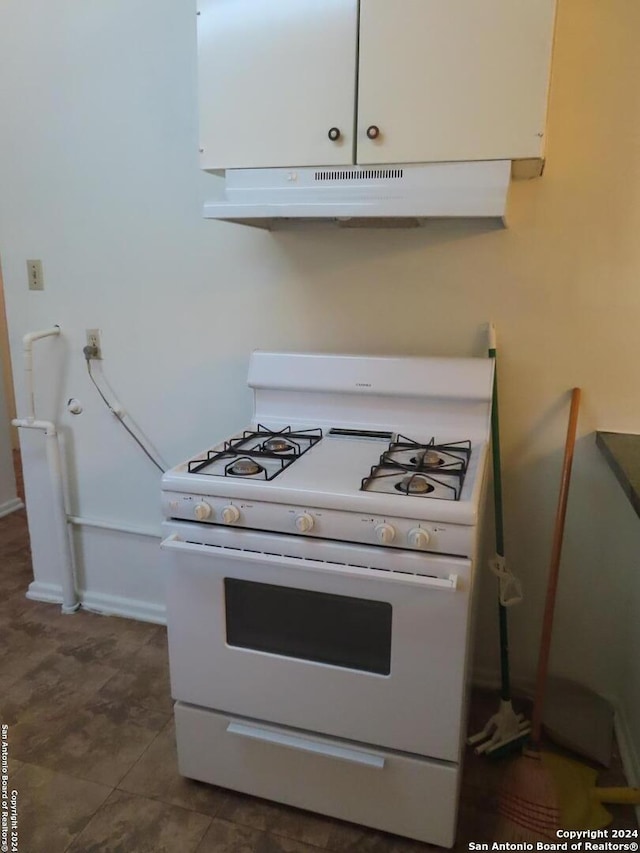 kitchen with white cabinets, white range with gas cooktop, and dark tile patterned flooring