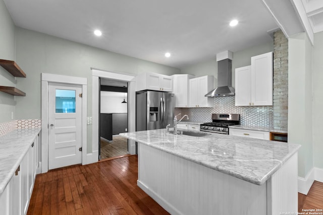 kitchen featuring appliances with stainless steel finishes, dark hardwood / wood-style floors, a kitchen island with sink, and wall chimney range hood