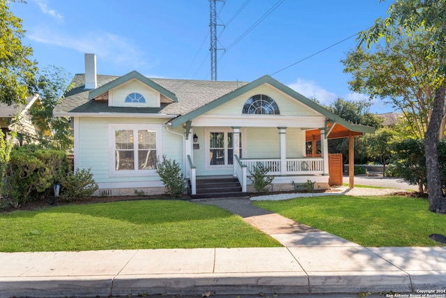 214 Loretta Pl, San Antonio, TX 78210 - view of front of home with covered porch, a front yard, a shingled roof, and a chimney