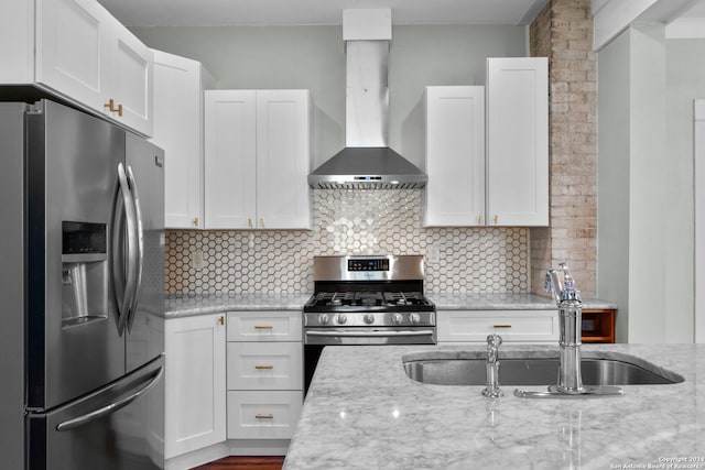 kitchen featuring light stone countertops, wall chimney exhaust hood, stainless steel appliances, sink, and white cabinetry