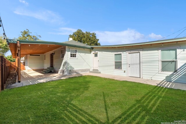 rear view of house with a carport and a yard