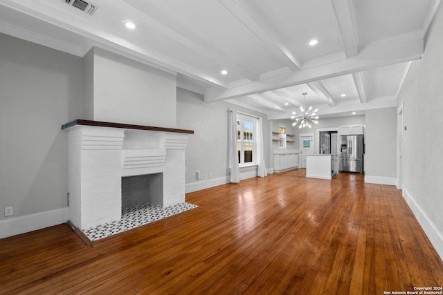 unfurnished living room with beamed ceiling, a notable chandelier, light hardwood / wood-style floors, and a fireplace