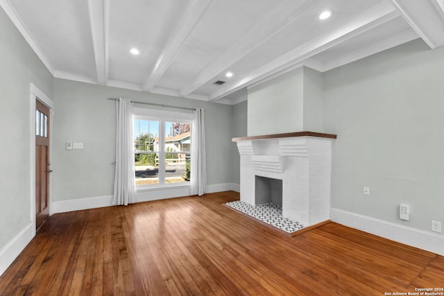 unfurnished living room featuring hardwood / wood-style floors, beam ceiling, crown molding, and a brick fireplace