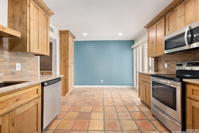 kitchen with light brown cabinets, light stone counters, stainless steel appliances, and tasteful backsplash