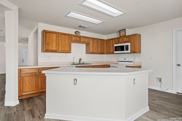 kitchen featuring a kitchen island, a textured ceiling, white appliances, and dark hardwood / wood-style flooring