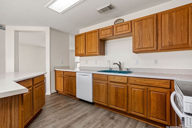 kitchen with white appliances, a textured ceiling, sink, and light wood-type flooring