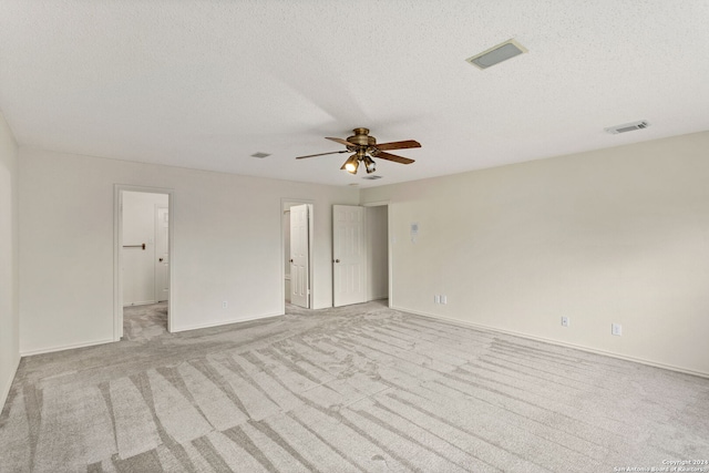 carpeted spare room featuring ceiling fan and a textured ceiling