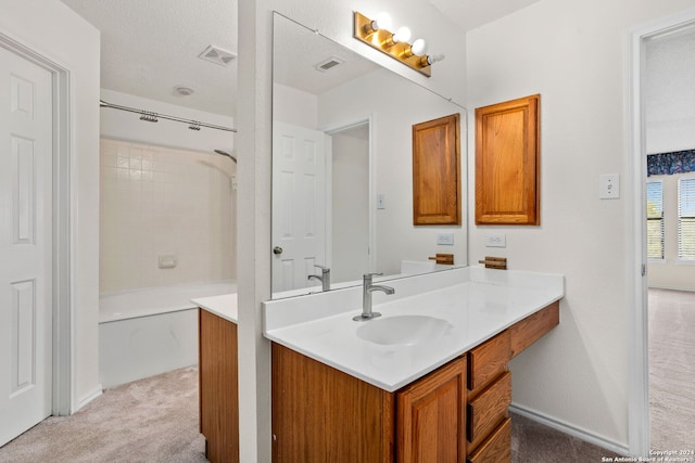 bathroom with tiled shower / bath, vanity, and a textured ceiling