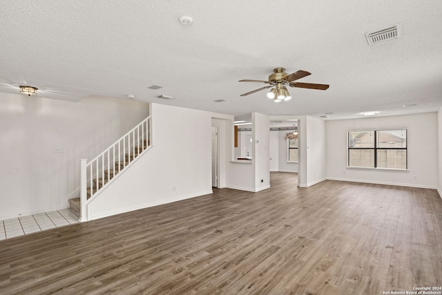 unfurnished living room with ceiling fan, wood-type flooring, and a textured ceiling