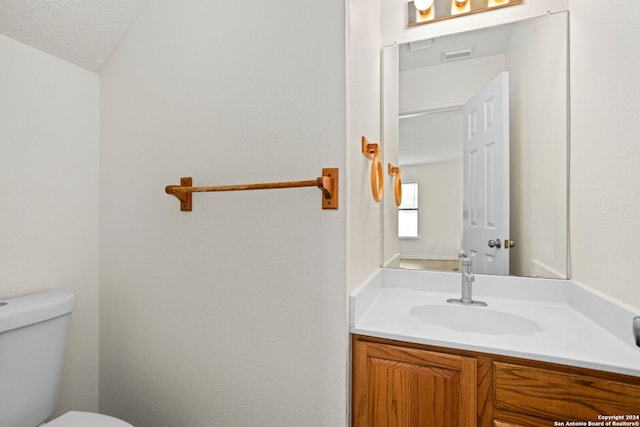 bathroom featuring toilet, a textured ceiling, vanity, and vaulted ceiling