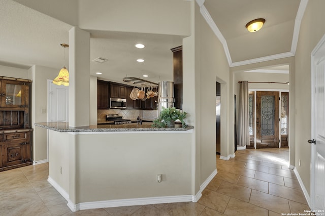 kitchen with dark brown cabinets, stainless steel appliances, ornamental molding, light stone countertops, and tasteful backsplash