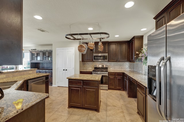 kitchen featuring stainless steel appliances, dark brown cabinets, and light stone counters