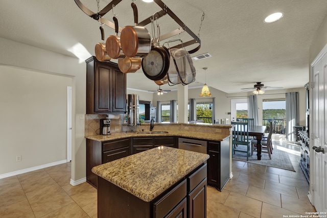 kitchen with kitchen peninsula, a kitchen island, a textured ceiling, pendant lighting, and dark brown cabinetry