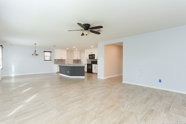 unfurnished living room with ceiling fan with notable chandelier