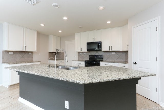 kitchen featuring white cabinetry, black appliances, sink, and an island with sink