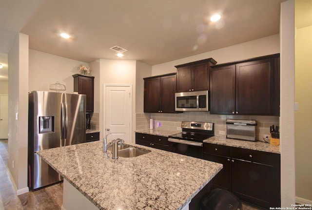 kitchen featuring sink, appliances with stainless steel finishes, dark brown cabinetry, and a kitchen island with sink