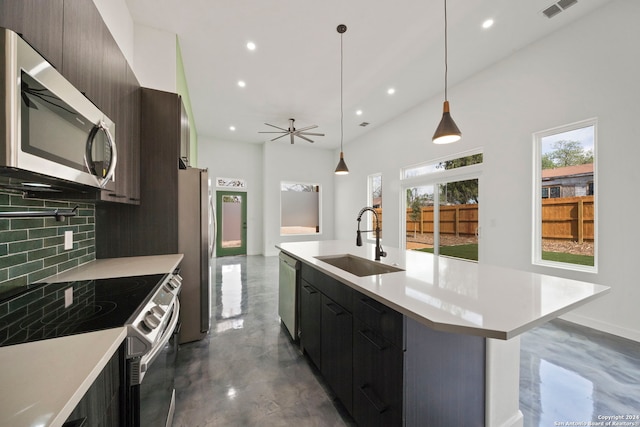 kitchen featuring tasteful backsplash, appliances with stainless steel finishes, sink, hanging light fixtures, and a center island with sink