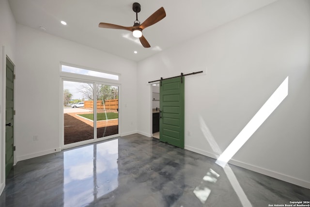 empty room featuring ceiling fan and a barn door