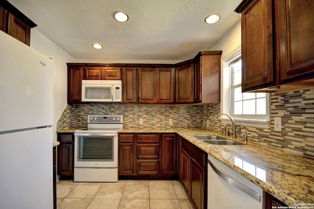 kitchen with white appliances, tasteful backsplash, sink, light stone counters, and light tile patterned floors