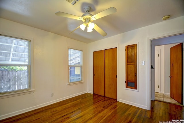 unfurnished bedroom with ceiling fan, a closet, and dark hardwood / wood-style flooring