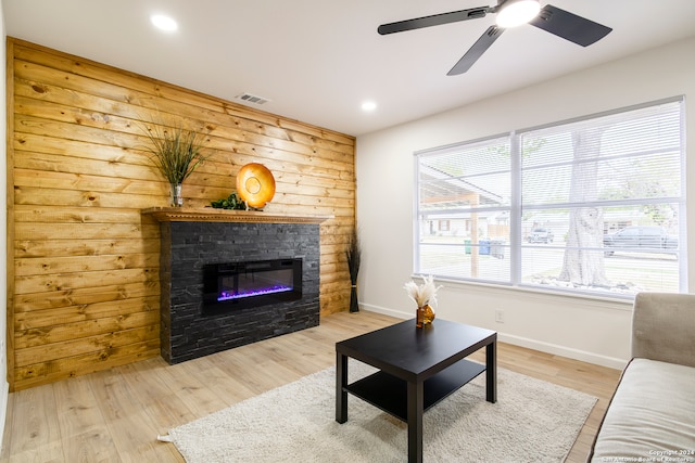 living room featuring a fireplace, light wood-type flooring, and ceiling fan