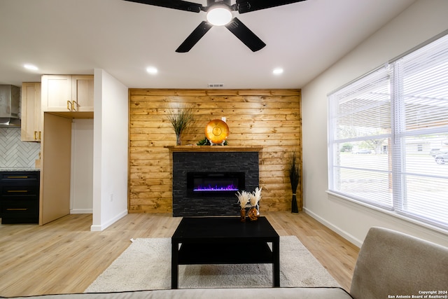 living room featuring light wood-type flooring, plenty of natural light, a fireplace, and wooden walls