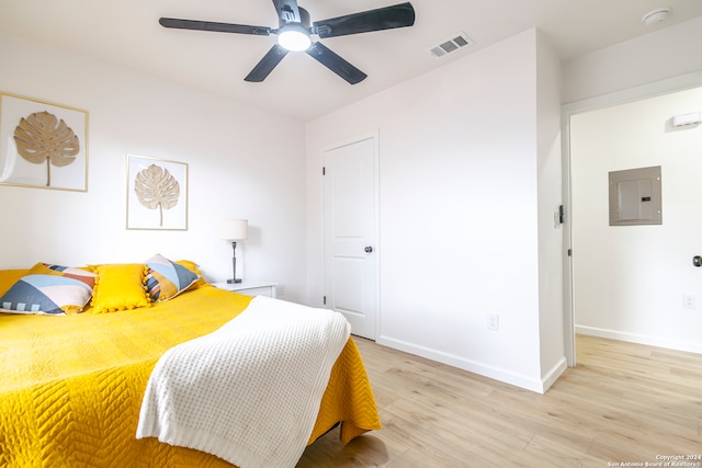 bedroom featuring light hardwood / wood-style floors, electric panel, and ceiling fan