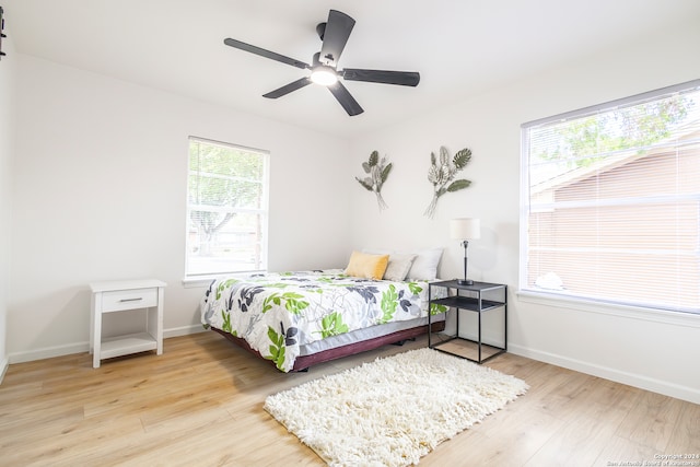 bedroom with ceiling fan, multiple windows, and light wood-type flooring