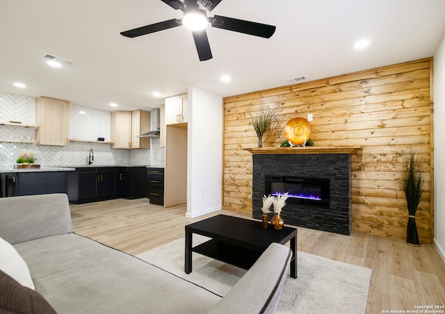 living room featuring light hardwood / wood-style floors, wood walls, a fireplace, and ceiling fan