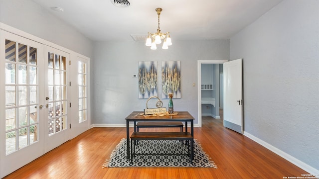 dining room featuring french doors, wood-type flooring, and a chandelier