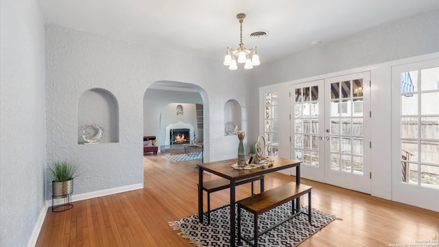 dining area with light hardwood / wood-style flooring, french doors, and a notable chandelier