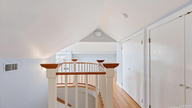 corridor with lofted ceiling and light hardwood / wood-style flooring