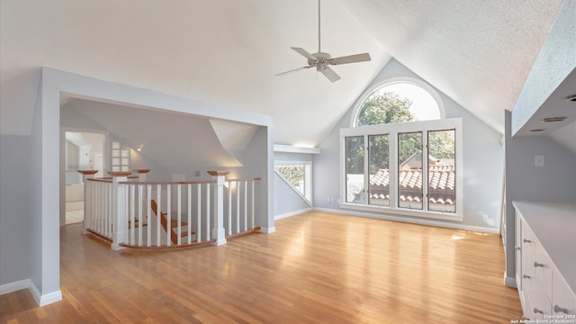 unfurnished living room featuring high vaulted ceiling, a textured ceiling, light hardwood / wood-style floors, and ceiling fan