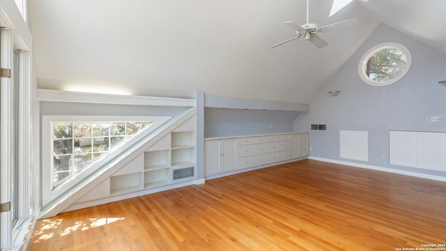 additional living space featuring lofted ceiling with skylight, light hardwood / wood-style flooring, and ceiling fan