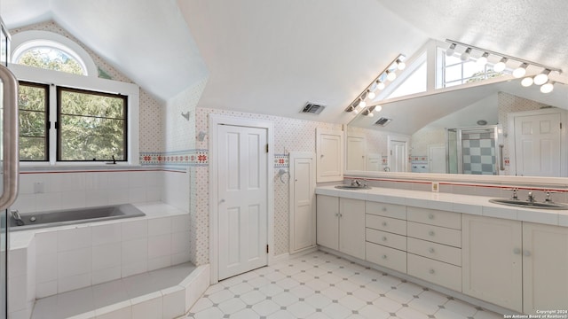 bathroom featuring vanity, track lighting, vaulted ceiling, and plus walk in shower